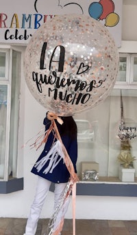 a woman holding a large balloon with the words'la quincenera mexicana'