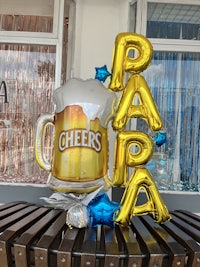 a beer mug decorated with balloons and confetti