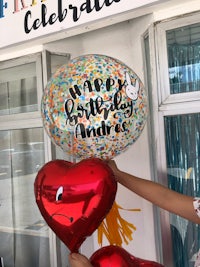 a woman is holding up balloons that say happy birthday