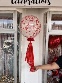 a woman is putting a red and white balloon in front of a store