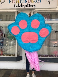 a woman with a blue and pink paw pinata in front of a store