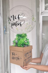 a woman holding a box with a balloon in it