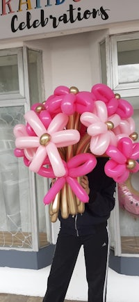 a woman holding a bouquet of pink and gold balloons