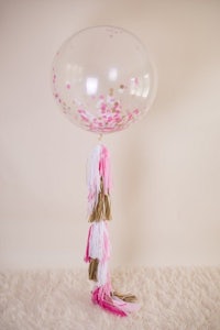 a pink and gold balloon with tassels