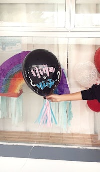 a woman holding up a balloon with the word unicorn on it