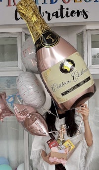 a woman holding a champagne bottle and balloons