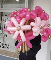 a woman holding a bouquet of pink and gold balloons