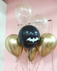 a bunch of gold and black balloons with a batman logo on them