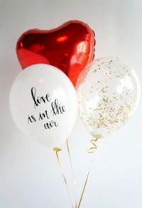 three balloons with the words love is in the air