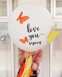 a woman holding up a balloon that says love you mom