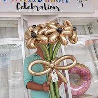 a man holding a bouquet of gold balloons in front of a store