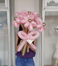 a woman holding a pink balloon bouquet in front of a store