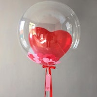 a heart shaped balloon with a red ribbon attached to it