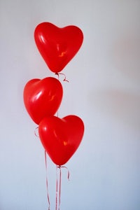 three red heart shaped balloons on a white background