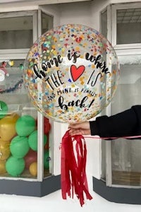 a person holding a balloon with confetti and tassels