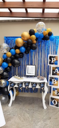 a table decorated with balloons and black and gold decorations