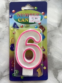 a pink and white number candle in a package